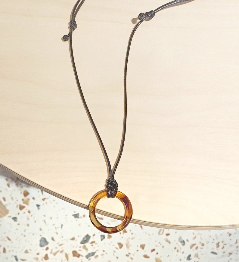 May include: A brown cord necklace with a tortoiseshell ring pendant.