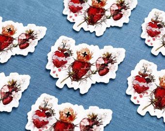 May include: Multiple die-cut stickers featuring a watercolor illustration of a Sacred Heart. Each sticker depicts a vibrant red heart encircled by a crown of thorns, topped with a small cross and flames, and accented with white floral blossoms.