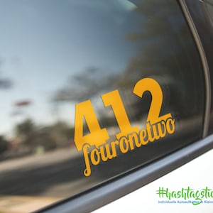 Könnte beinhalten: Ein gelber Vinyl-Aufkleber mit der Nummer 412 und dem Text "fouronetwo" auf einem Autofenster. Der Aufkleber befindet sich auf einem schwarzen Hintergrund und der Text ist in einer kursivschriftlichen Schriftart. Der Aufkleber stammt von der Website hashtag sticker.de.