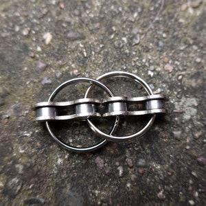May include: A silver chain keychain with two interlocking rings. The chain is made of metal links and the rings are smooth and round.