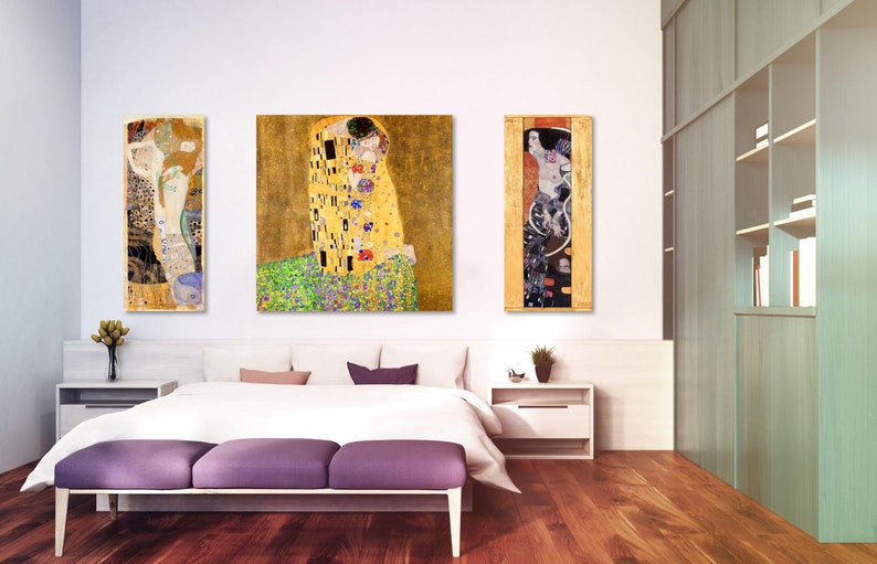 Puede incluir: Tres pinturas enmarcadas de obras de arte famosas de Gustav Klimt. Las pinturas est&aacute;n colgadas en una pared blanca sobre una cama con ropa de cama blanca y un piecero morado. Las pinturas son todas en un estilo similar, con acentos dorados y negros.
