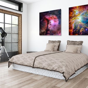 Puede incluir: Un interior de dormitorio con una cama, dos almohadas, una mesita de noche y un telescopio. Dos im&aacute;genes enmarcadas de nebulosas coloridas cuelgan en la pared sobre la cama.