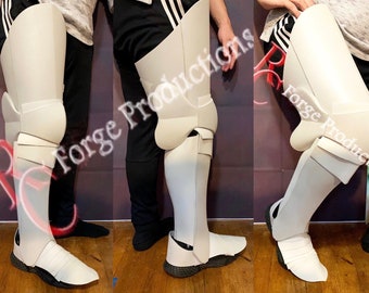 May include: White foam leg armor with straps and buckles. The armor is worn on a person's left leg and extends from the knee to the ankle.