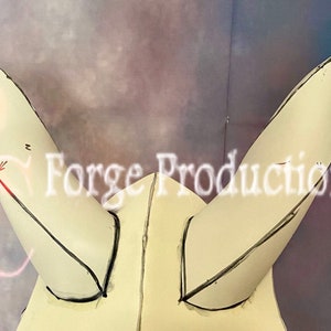 Può includere: Due corna di schiuma bianca con linee nere disegnate su di esse. Le corna sono attaccate a una base di schiuma bianca. Il testo "Forge Productions" è visibile sullo sfondo.