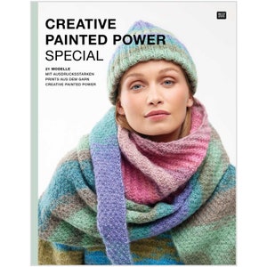 Könnte beinhalten: Ein Buchcover mit einer Frau, die eine bunte Strickmütze und einen Schal trägt. Der Titel des Buches lautet "Creative Painted Power Special" mit dem Untertitel "21 Modelle mit ausdrucksstarken Prints aus dem Garn Creative Painted Power".