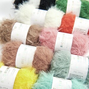 Könnte beinhalten: Eine Sammlung flauschiger Garnknäuel in verschiedenen Farben, darunter Weiß, Schwarz, Braun, Rosa, Orange, Grün, Gelb und Türkis. Jedes Knäuel hat ein Etikett mit dem Markennamen "RICORUMI" und dem Gewicht und der Länge des Garns.