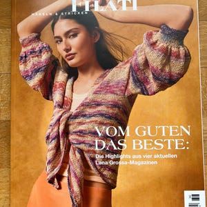 May include: A Lana Grossa Filati magazine cover featuring a multi-colored knit cardigan with long sleeves and a tie-front closure. The text reads Lana Grossa Filati, Häkeln & Stricken, and Vom Guten das Beste: Die Highlights aus vier aktuellen Lana Grossa-Magazinen.