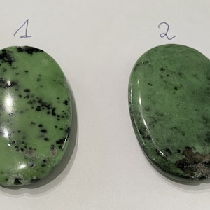 Könnte beinhalten: Zwei grüne, oval geformte Steine mit schwarzen Flecken. Der Stein links hat mehr schwarze Flecken als der Stein rechts. Die Steine sind mit "1" und "2" beschriftet.