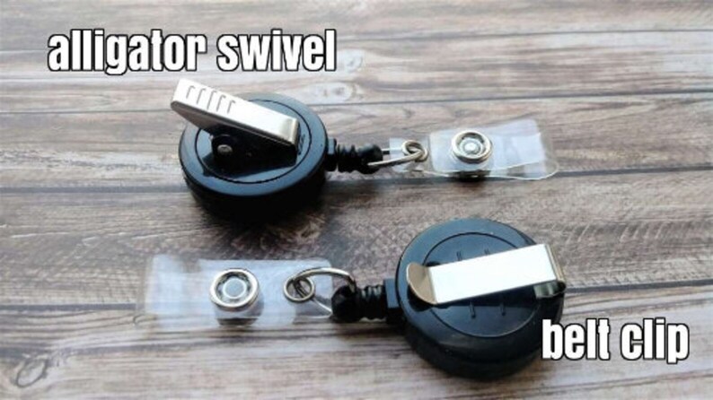May include: Two black retractable badge reels with alligator clips and belt clips. The reels have a clear plastic strap with a metal swivel.