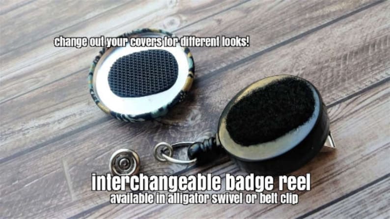 May include: Interchangeable badge reel with a black and white patterned fabric cover. The reel has a black retractable cord and a black alligator clip. The text "change out your covers for different looks!" and "interchangeable badge reel available in alligator swivel or belt clip" is visible in the image.