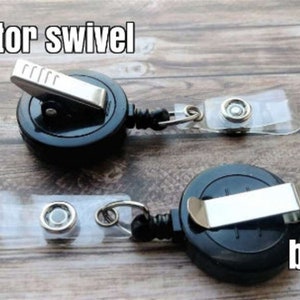 May include: Two black retractable badge reels with alligator clips and belt clips. The reels have a clear plastic strap with a metal swivel.