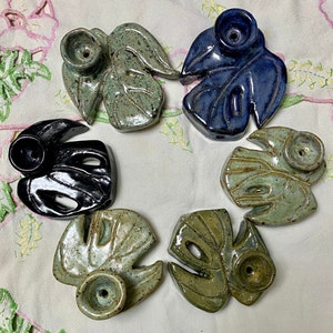 May include: Six ceramic leaf-shaped incense holders in various shades of green, blue, and black. Each holder has a small hole in the center for burning incense.