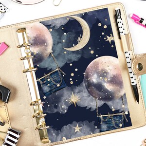 May include: A gold binder with a dark blue cover featuring a watercolor design of moons, stars, and clouds. The design includes gold glitter accents and a gold crescent moon.