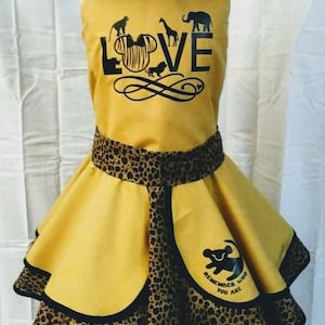 May include: Yellow and black animal print dress with a black and white graphic of Mickey Mouse and the words "Love" and "Remember who you are". The dress has a black trim and a matching hat with a yellow bow.