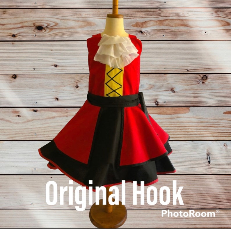 May include: A red and black dress with a white ruffle collar and a yellow and black design on the bodice. The dress has a black belt and a black and red skirt. The dress is on a wooden mannequin. The text "Original Hook" is at the bottom of the image.