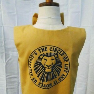 May include: A yellow sleeveless shirt with a black circle design featuring a lion's face and the text "It's the Circle of Life and It Moves Us All".