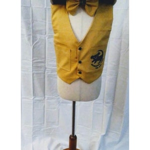 May include: A yellow vest with a pocket on each side and a black button closure. The vest has an embroidered image of a lion with the text "Remember You Are Brave" on the front. The vest is on a white mannequin with a brown wooden base. The mannequin is wearing a brown and black leopard print hat with black Mickey Mouse ears and a yellow bow tie.
