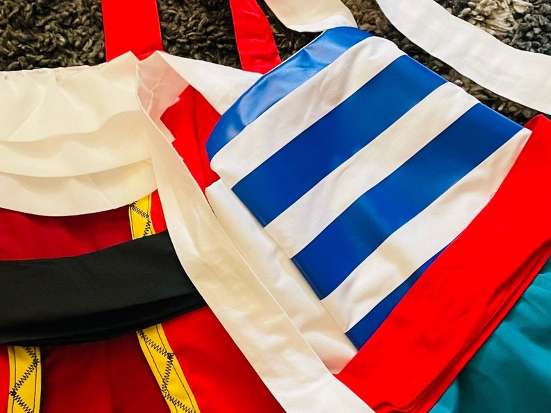 May include: A red, white, and blue striped fabric with a red and yellow trim. The fabric is folded in half and has a white fabric underneath.