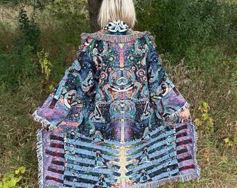 May include: A long, patterned coat with a vibrant, colorful design. The coat features a detailed, psychedelic pattern in shades of blue, purple, green, and orange. It has a fringed hem and collar, and is worn outdoors.