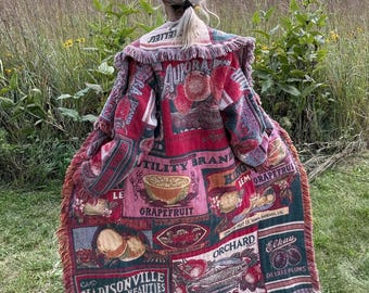 May include: A long, open-front coat made from a woven tapestry fabric featuring a collage of vintage fruit crate labels. The design includes text such as Aurora Brand, Utility Brand, Grapefruit, Orchard, Pears, Madisonville Beauties, and Elkay.
