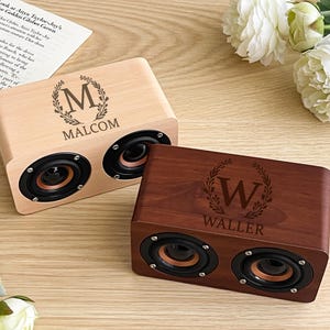Può includere: Due altoparlanti in legno, uno chiaro e uno scuro, ciascuno con due coni. L'altoparlante chiaro ha incisi "M" e "MALCOM", mentre quello scuro ha "W" e "WALLER". Un motivo floreale circonda le lettere.