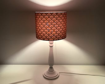 May include: A white table lamp with a brown and orange patterned lampshade. The lampshade has a geometric design.