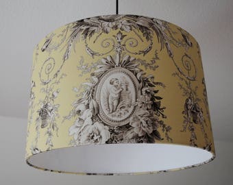 May include: A yellow lampshade with a white inner lining. The lampshade features a black and white floral pattern with a cherub design in the center.