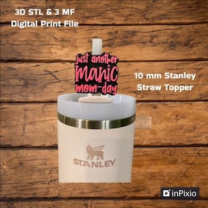 May include: A white Stanley travel mug with a black and pink straw topper that says "Just another manic mom-day". The straw topper is 10 mm in diameter.