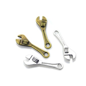 May include: Three miniature wrench charms, two in antique gold and one in silver. The wrenches have a detailed design and are perfect for adding a touch of industrial style to jewelry or crafts.