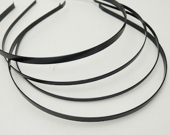 May include: Four black metal headbands, each with a simple, smooth design. The headbands are stacked on top of each other.
