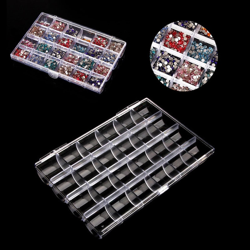 May include: A clear plastic storage box with multiple compartments for organizing small items. The box is filled with colorful rhinestones.
