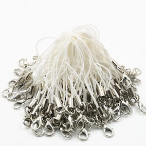 Puede incluir: Un paquete a granel de charms de teléfono de cuerda blanca con cierres de langosta de metal plateado.