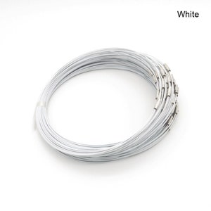 May include: A close-up of a stack of white metal necklace chains. The chains are coiled and have silver-toned clasps.