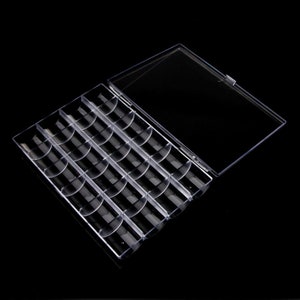 May include: A clear plastic storage box with a lid. The box has 24 compartments for storing small items.
