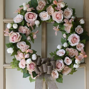 Wreath with soft pink, peach and white roses interspersed with alstroemeria lilies tied off with a gold edged burlap bow