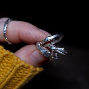 May include: Three silver rings with a textured, hammered finish. The rings are stacked on top of each other.