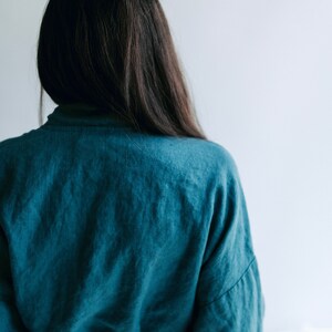 May include: A person wearing a teal blue robe with long sleeves and a tie belt.