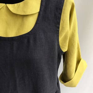 May include: A black linen dress with a yellow linen collar and short sleeves. The dress has a gathered skirt and a scoop neckline.