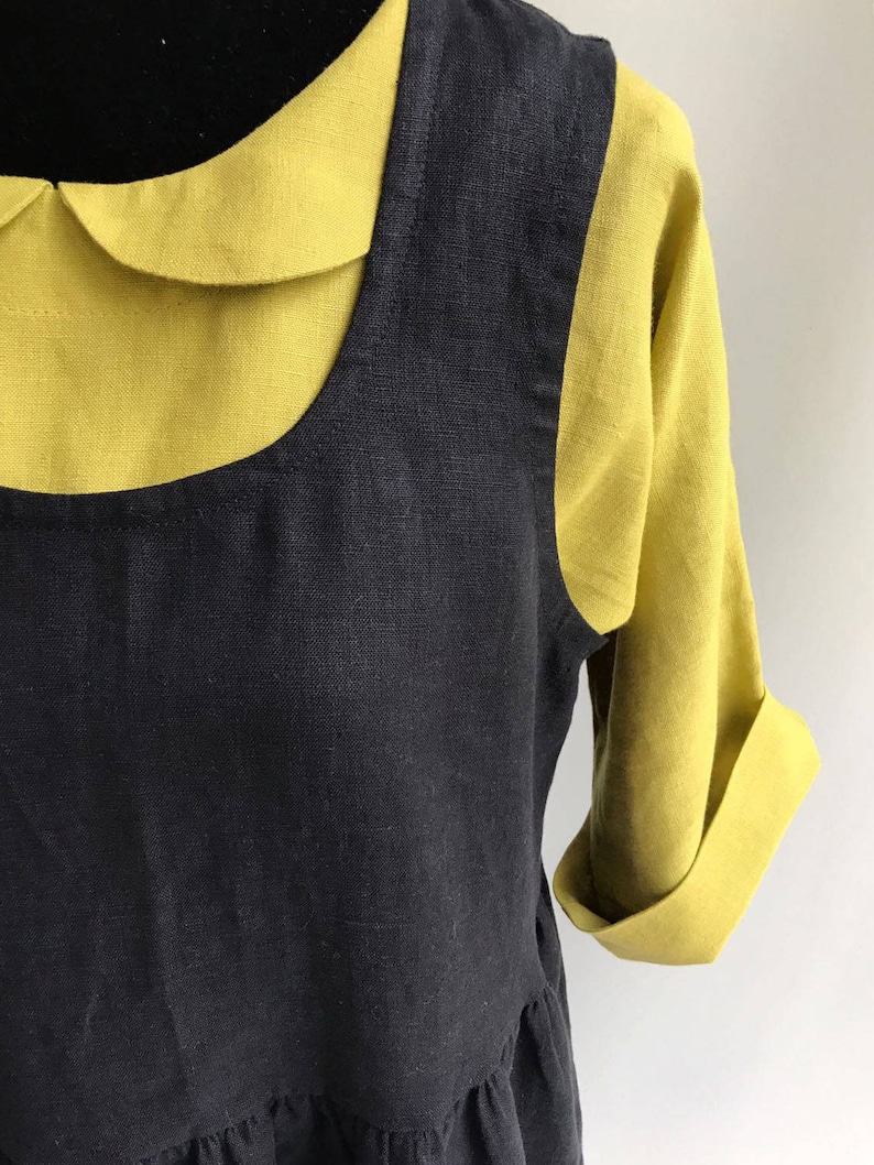 May include: A black linen dress with a yellow linen collar and short sleeves. The dress has a gathered skirt and a scoop neckline.