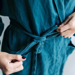May include: A teal blue robe with a self-tie sash. The robe is made of a soft, textured fabric.