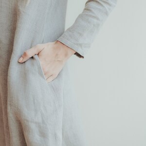 May include: A gray linen dress with a long sleeve and a pocket on the side.