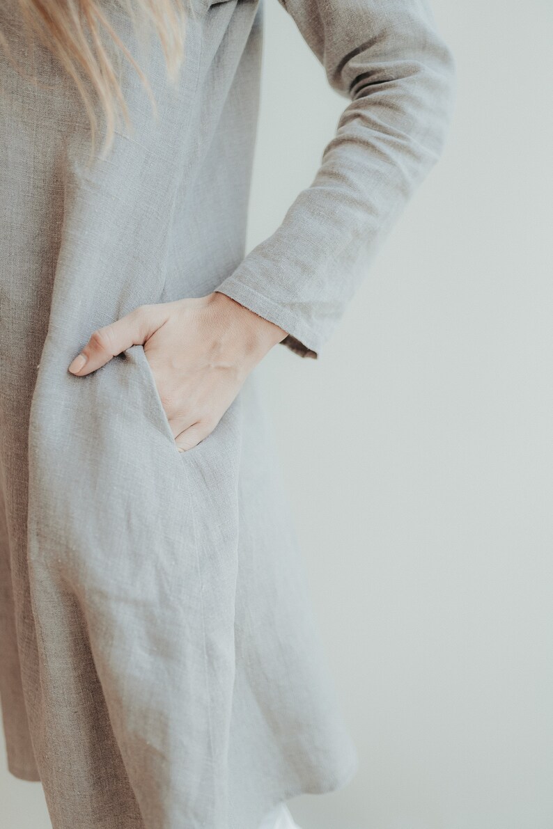 May include: A gray linen dress with a long sleeve and a pocket on the side.