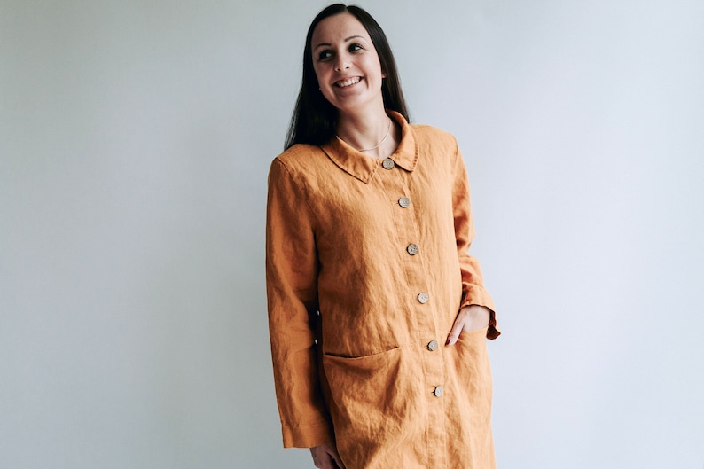May include: A long-sleeved, button-up shirt in a warm orange color. The shirt has a collared neckline and a relaxed fit.