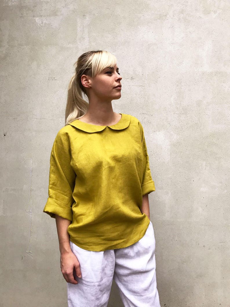 May include: A mustard yellow linen blouse with a peter pan collar and three-quarter sleeves.
