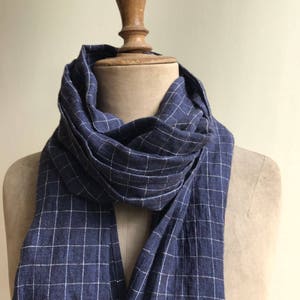 May include: A navy blue and white checked scarf made of linen. The scarf is folded and draped over a mannequin's neck.