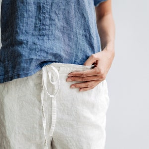 May include: A white linen pants with a drawstring waist and a blue linen shirt.