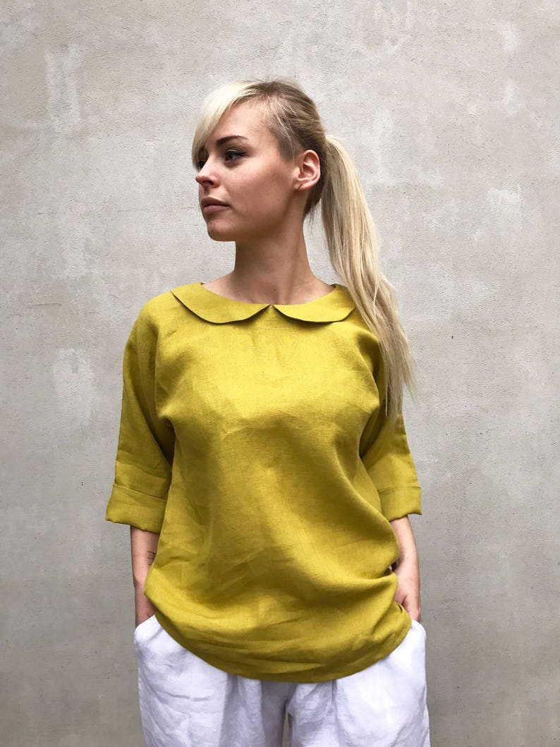 May include: A mustard yellow linen blouse with a peter pan collar and 3/4 sleeves.