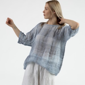 Può includere: Una blusa di lino a quadri blu e bianchi, con una vestibilità rilassata e maniche a 3/4.