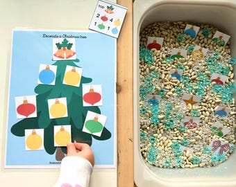 May include: A Christmas-themed educational activity. A green Christmas tree illustration with colorful ornament cutouts. A white bin filled with beans, blue snowflake decorations, and ornament cards. The text "Decorate a Christmas tree" is visible.