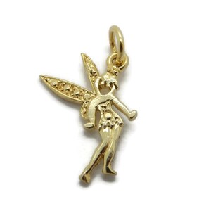 Peut inclure: Un charm en forme de fée de couleur or, avec les bras tendus et des ailes détaillées. Le charm est un pendentif avec une boucle en haut pour l'attacher à un collier ou un bracelet. La fée est dans une pose gracieuse.